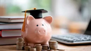 Imagen de la Beca Medrano: alcancía con birrete y libros que simbolizan ayuda económica para estudios.